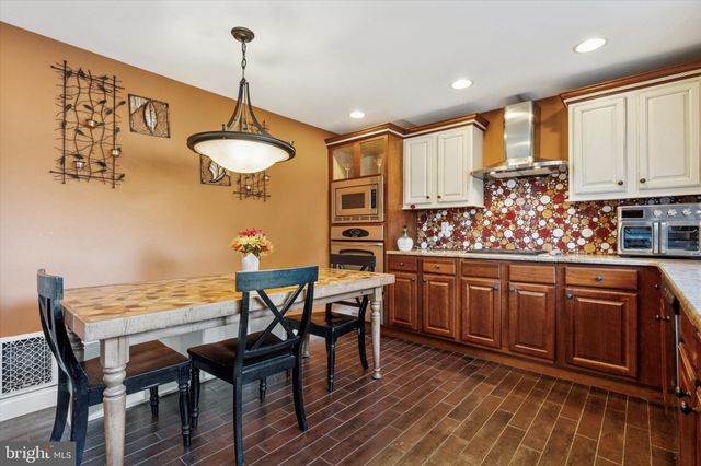 a kitchen with stainless steel appliances granite countertop a stove top oven a refrigerator and wooden cabinets