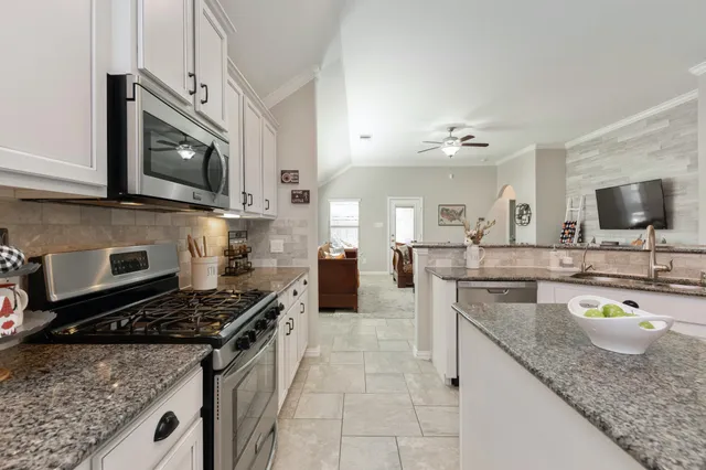a kitchen with stainless steel appliances granite countertop a stove microwave and sink