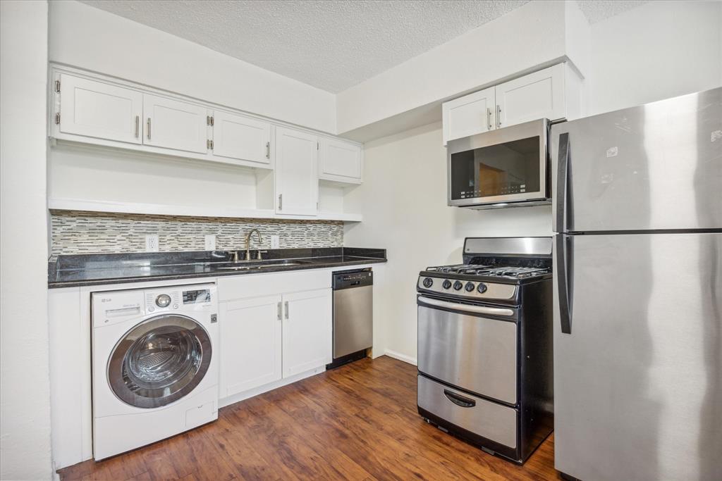 a kitchen with white cabinets stainless steel appliances and wooden floor