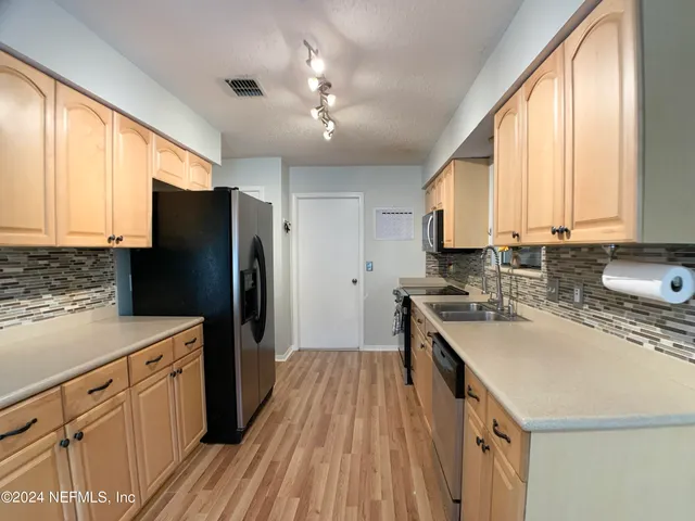 a kitchen with a stove a sink dishwasher a refrigerator and cabinets with wooden floor