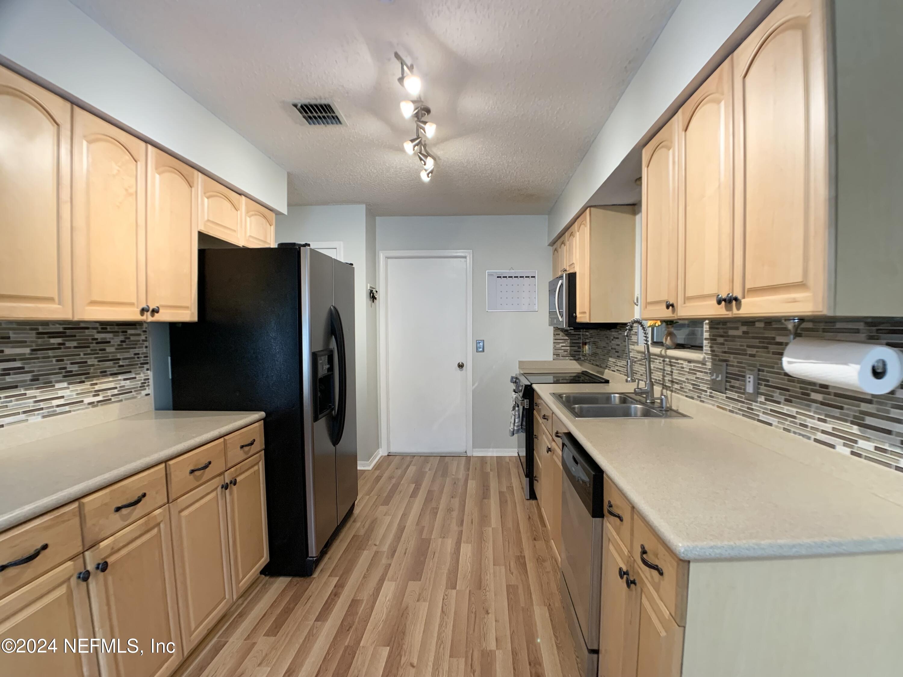 3149 Lakeside Villa Road Orange Park, FL 32073 - Photo 12 of 42 a kitchen with a stove a sink dishwasher a refrigerator and cabinets with wooden floor