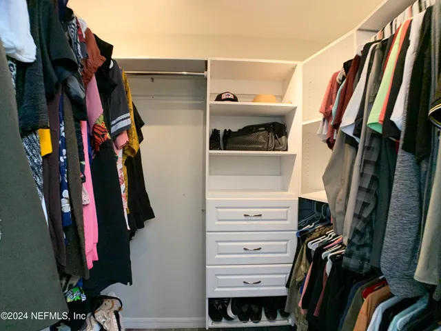 a view of walk in closet with clothes and shoes