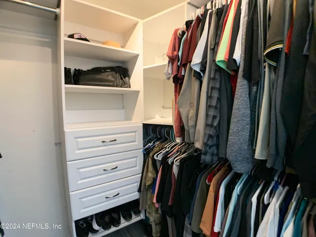 a view of walk in closet with clothes and shoes