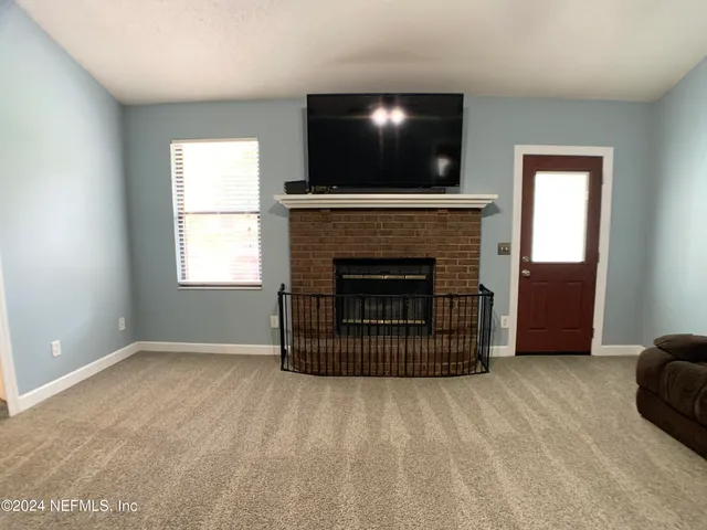 a view of an empty room with a fireplace and window