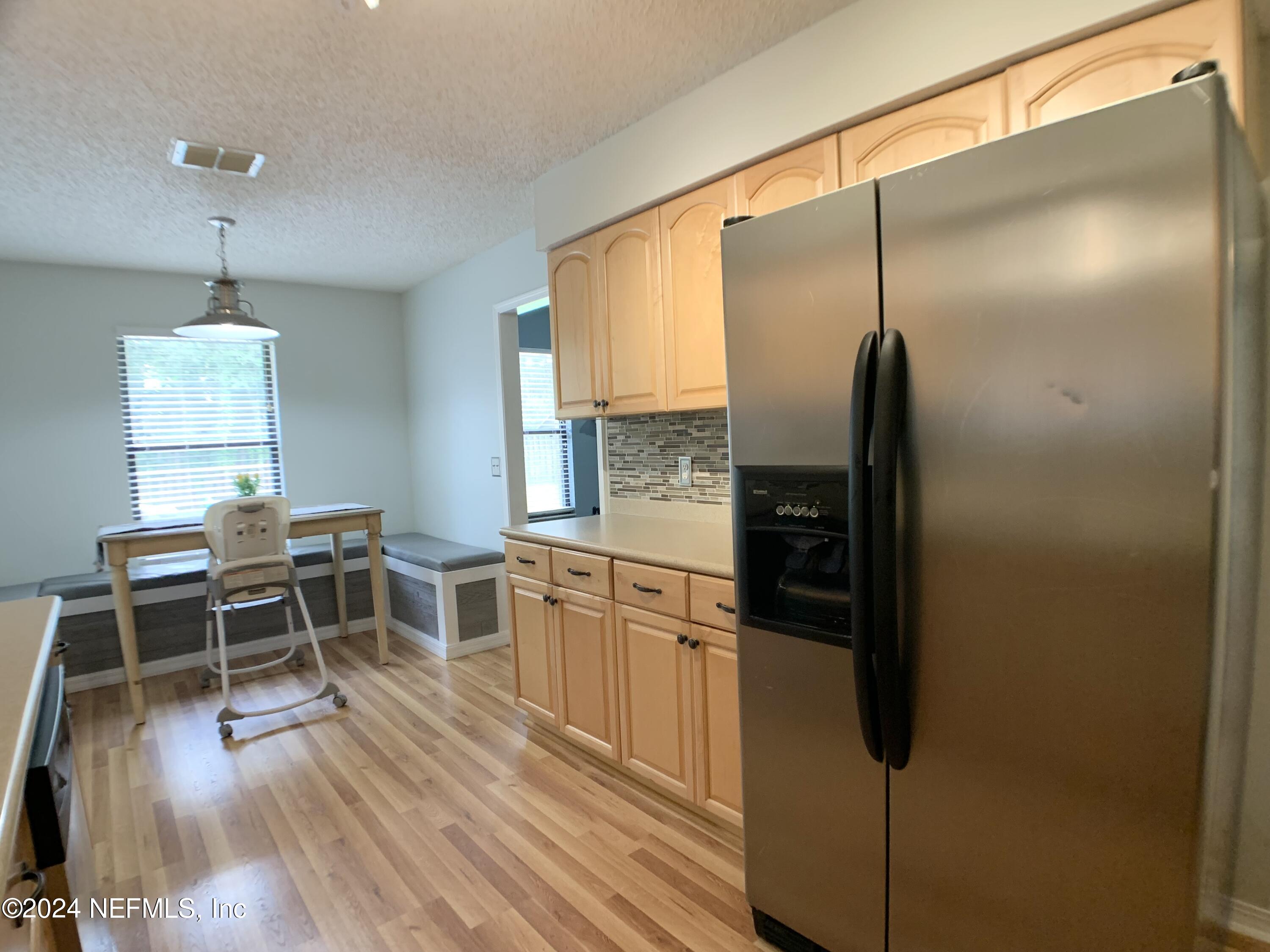 3149 Lakeside Villa Road Orange Park, FL 32073 - Photo 10 of 42 a kitchen with stainless steel appliances granite countertop a refrigerator a stove a kitchen island a dining table and chairs with wooden floor