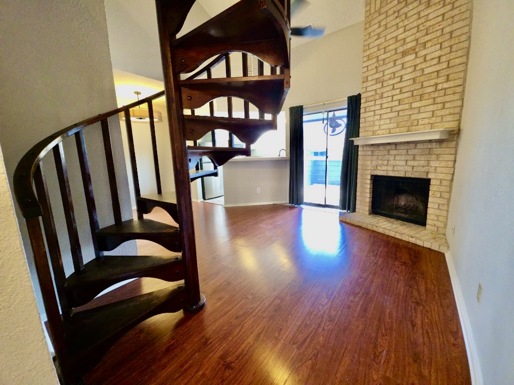2500 Burleson Road, Unit 521 Austin, TX 78741 - Photo 3 of 20 Spiral staircase with wood-finish treads, wood-finish flooring, a brick-faced fireplace, a white mantel, and sliding glass doors