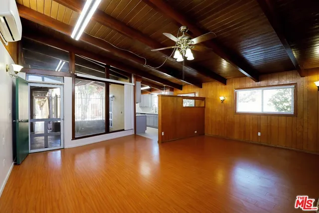a view of an empty room with wooden floor and a ceiling fan