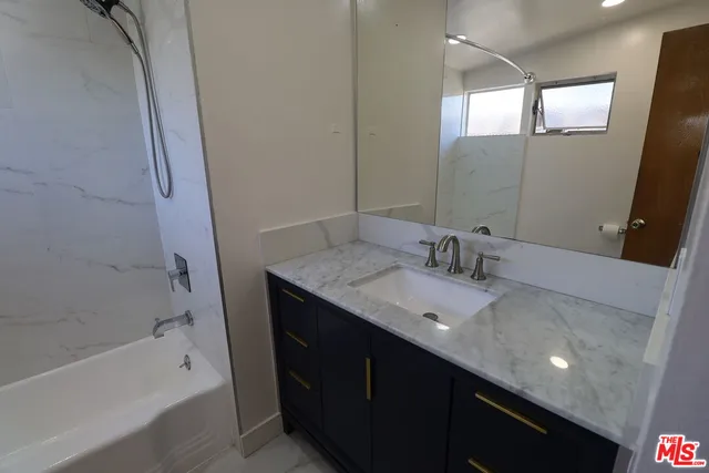 a bathroom with a granite countertop sink a mirror and a bathtub