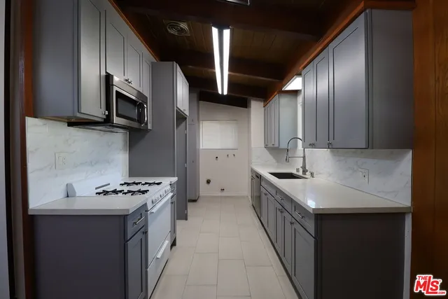 a kitchen with stainless steel appliances a sink dishwasher a stove top oven a refrigerator with island and cabinets