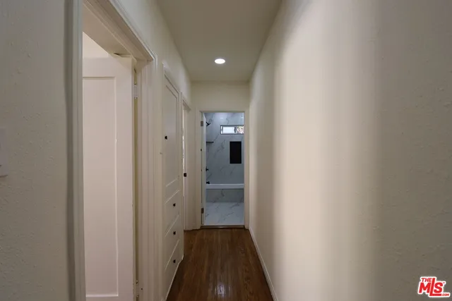 a view of a hallway with wooden floor and a bathroom