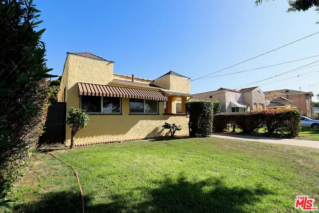 a view of a house with a big yard potted plants and a large tree