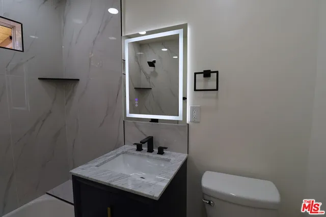 a bathroom with a granite countertop toilet and sink