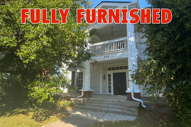 a front view of a house with a yard and potted plants