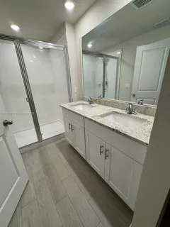 a bathroom with a granite countertop sink a mirror and a shower