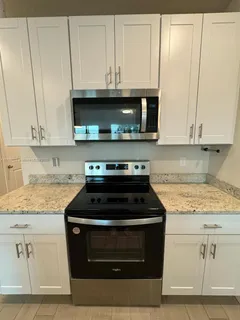 a kitchen with granite countertop white cabinets and a stove top oven
