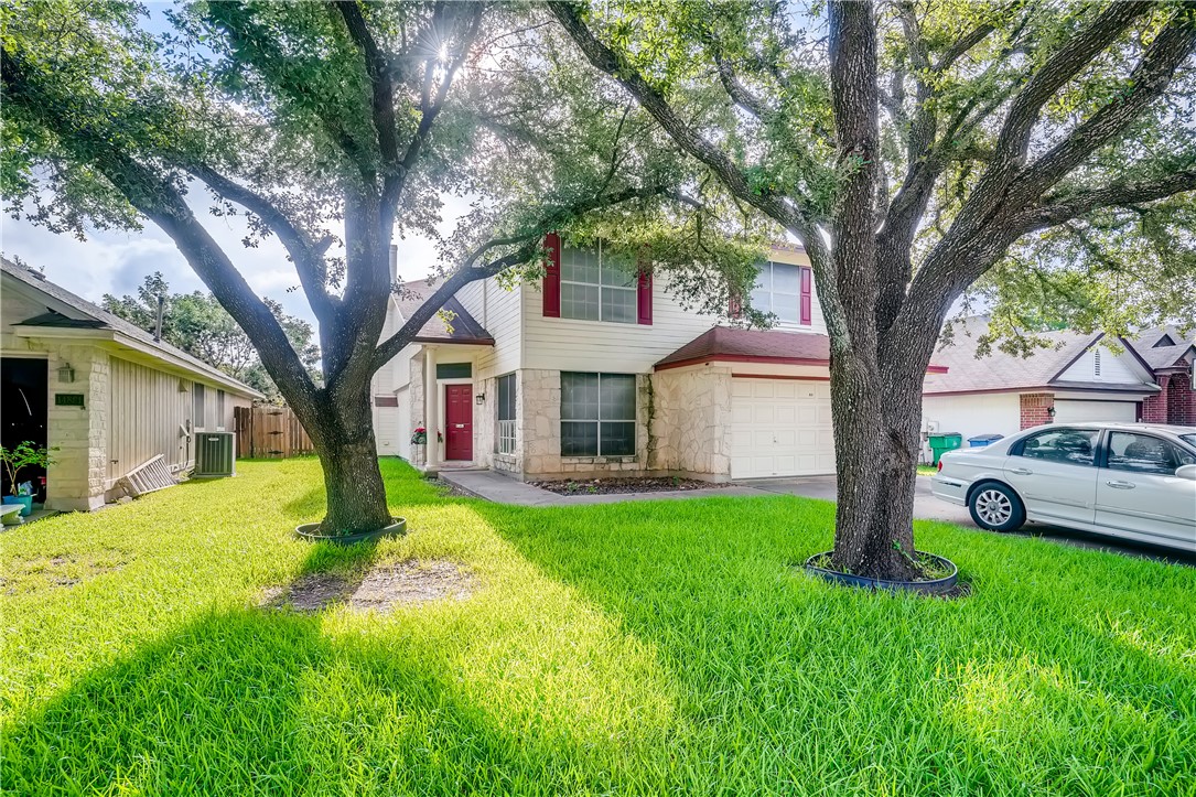 a view of a house with a big yard and large tree