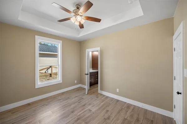 an empty room with windows and a ceiling fan