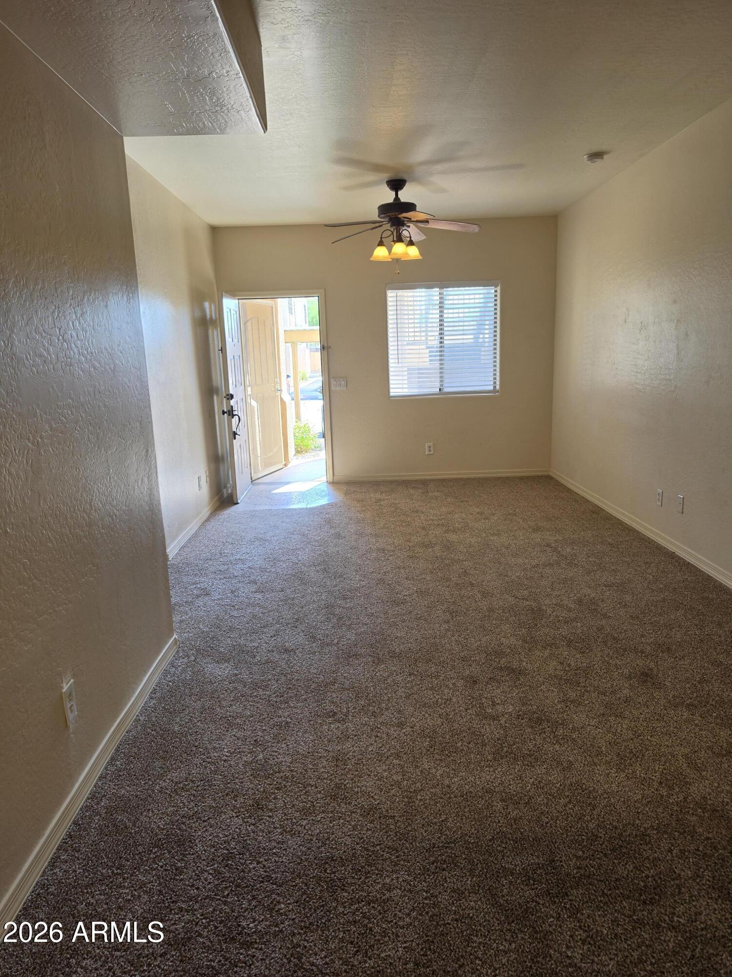 537 South Delaware Drive, Unit 104 Apache Junction, AZ 85120 - Photo 4 of 19 an empty room with windows and chandelier fan