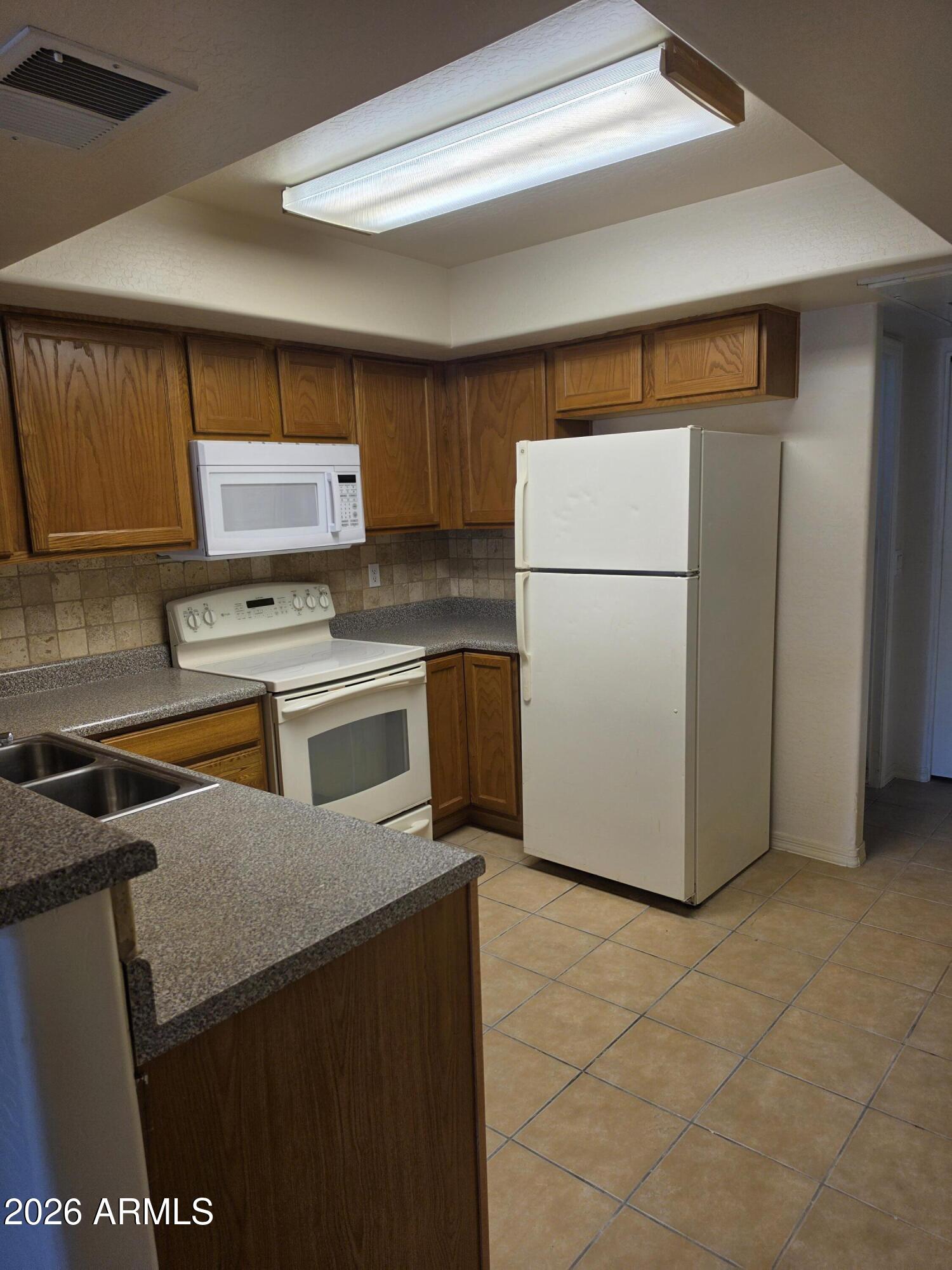537 South Delaware Drive, Unit 104 Apache Junction, AZ 85120 - Photo 6 of 19 a kitchen with a refrigerator sink stove and cabinets