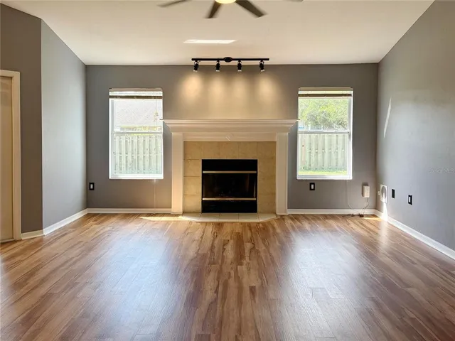 an empty room with wooden floor fireplace and windows