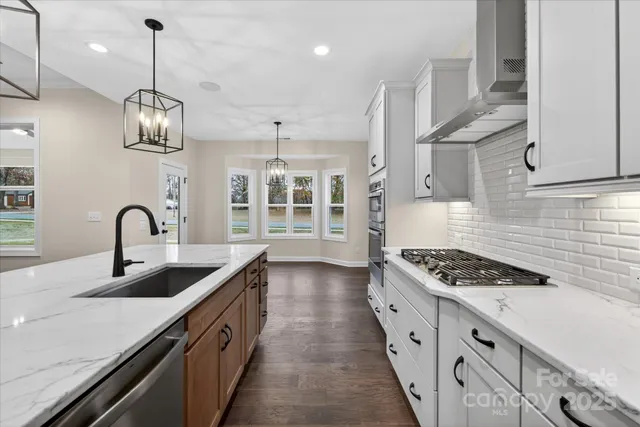 a kitchen with kitchen island a sink stove a refrigerator and white cabinets with wooden floor