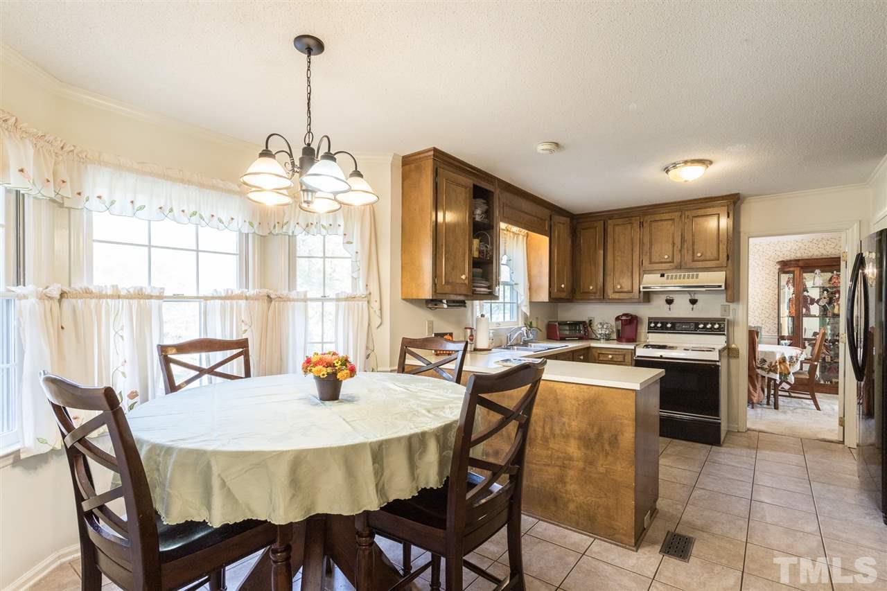 5363 Russell Road Durham, NC 27712 - Photo 12 of 28 a kitchen with stainless steel appliances granite countertop a stove a sink dishwasher a dining table and chairs with wooden floor