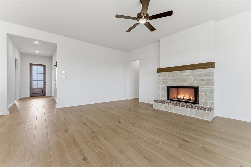 114 Brandywine Trail Rhome, TX 76078 - Photo 16 of 27 a view of an empty room with wooden floor a fireplace and a window