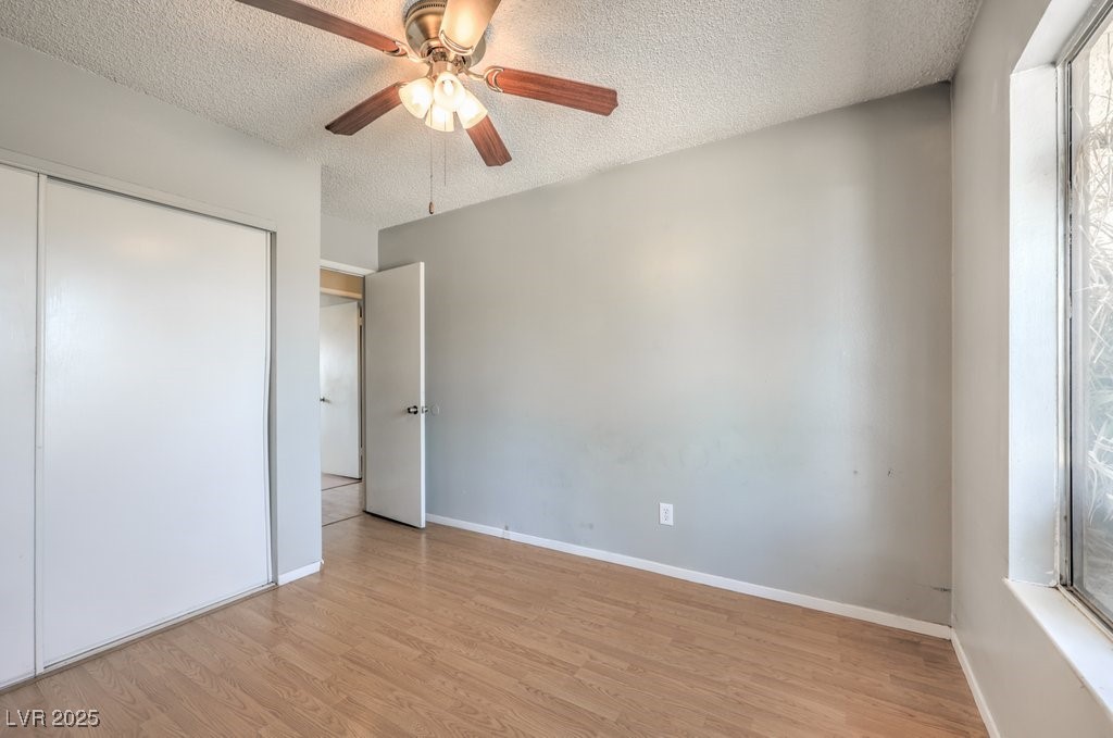 3948 Maple Hill Road Las Vegas, NV 89115 - Photo 10 of 20 Unfurnished bedroom with light wood-type flooring, a closet, baseboards, and a textured ceiling