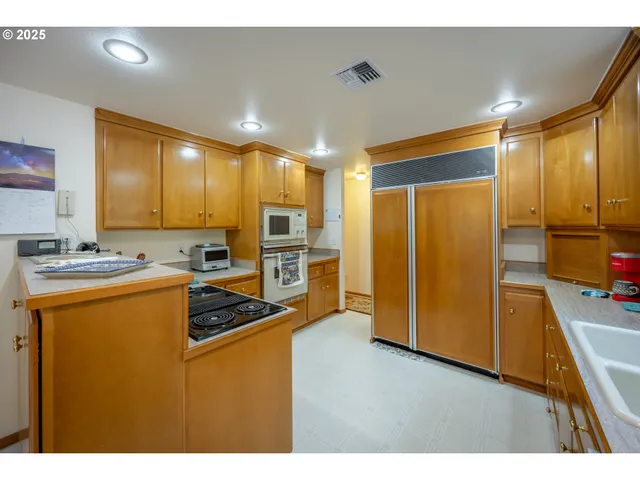 a kitchen with stainless steel appliances granite countertop a refrigerator a stove and a sink with wooden floor