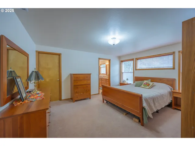 a bedroom with a bed and large windows