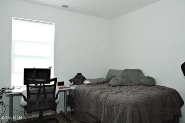 a bed room with a bed a chair and a computer