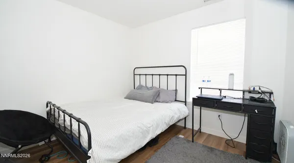 a bedroom with a bed a dresser with wooden floor