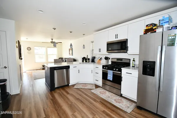a kitchen with a refrigerator stove and wooden floor