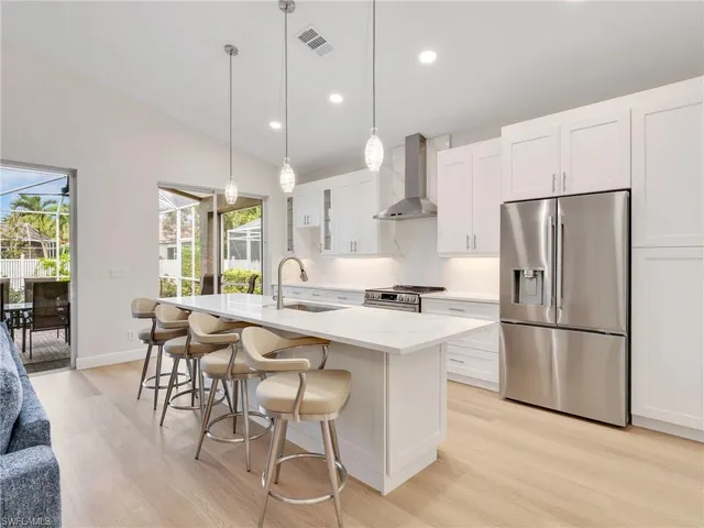 a kitchen with stainless steel appliances a refrigerator a stove a sink a dining table and chairs