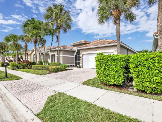 a front view of a house with a garden and palm trees