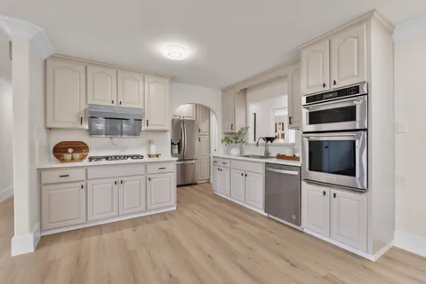 a kitchen with granite countertop white cabinets and stainless steel appliances