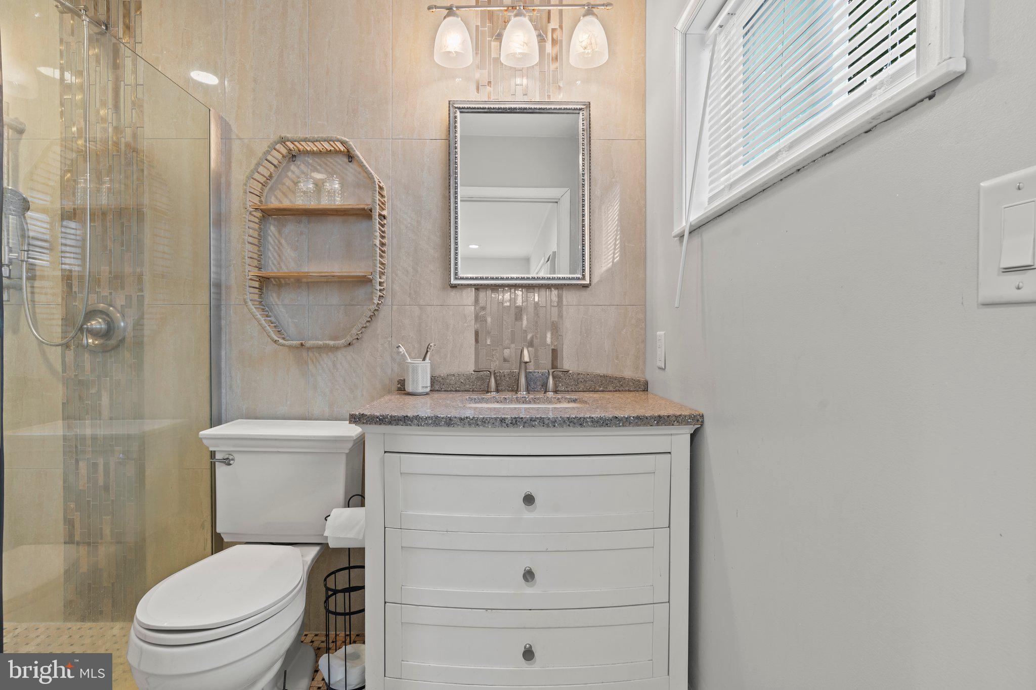 30 Roving Road Levittown, PA 19056 - Photo 19 of 40 a bathroom with a granite countertop toilet sink shower and mirror