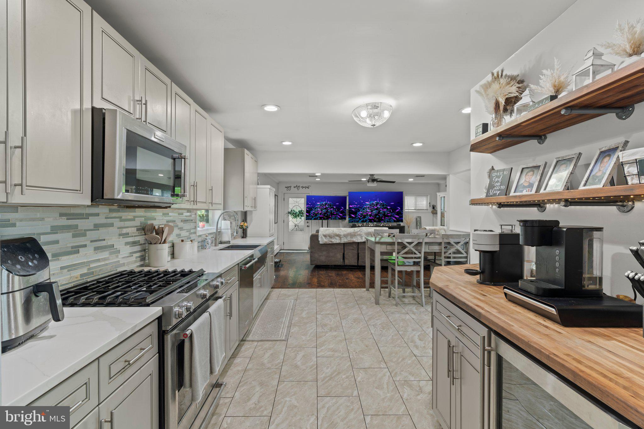 30 Roving Road Levittown, PA 19056 - Photo 7 of 40 a kitchen with stainless steel appliances granite countertop a stove top oven a sink dishwasher a dining table and chairs with wooden floor