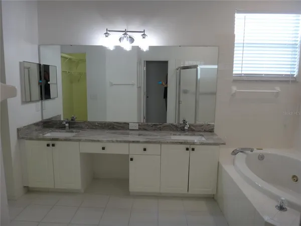 a bathroom with a granite countertop bathtub a sink and a large mirror