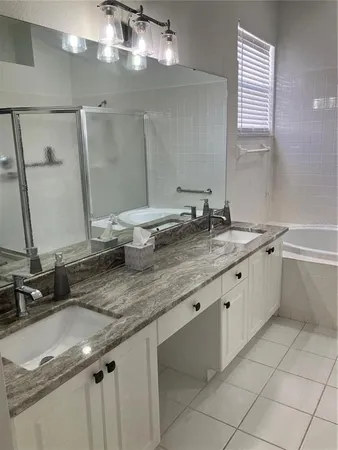 a bathroom with a granite countertop sink a large mirror and a bathtub