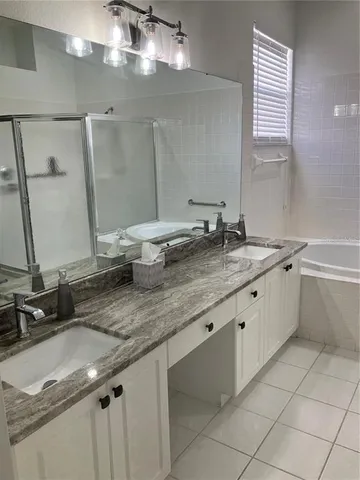 a bathroom with a granite countertop sink a large mirror and a bathtub