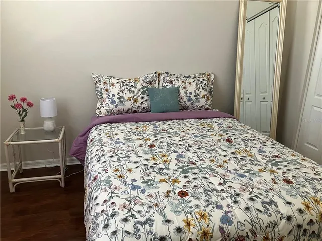 a bedroom with a bed and a dresser with wooden floor