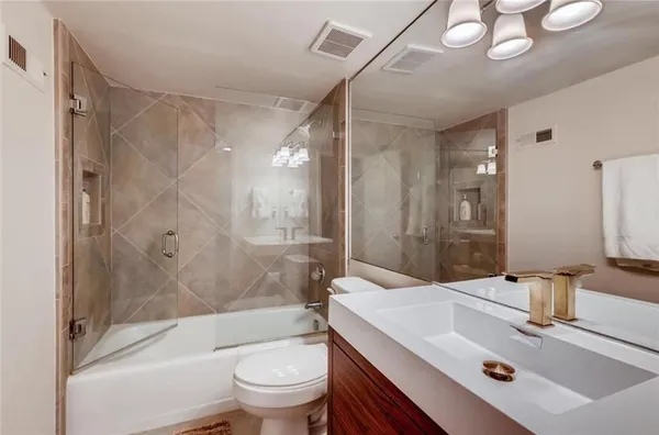 a bathroom with a sink a toilet a mirror and shower