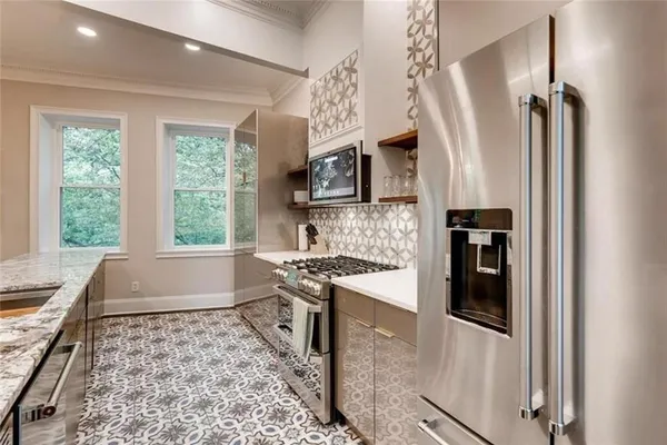 a kitchen with stainless steel appliances granite countertop a refrigerator a stove a sink and a window