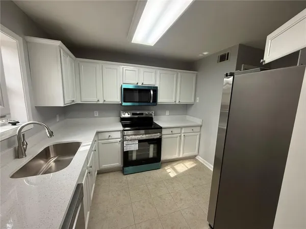 a kitchen with white cabinets sink and stainless steel appliances