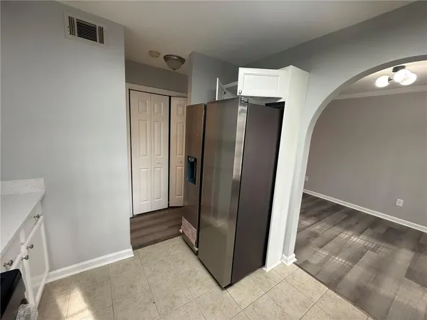 a view of a refrigerator in kitchen and an empty room
