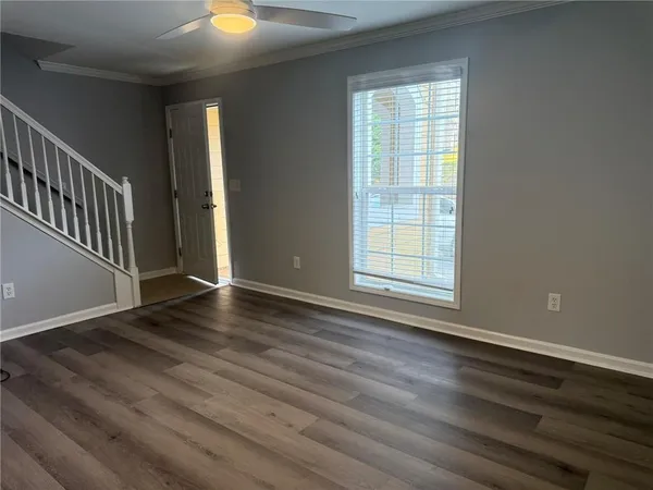 a view of an empty room with wooden floor and a window
