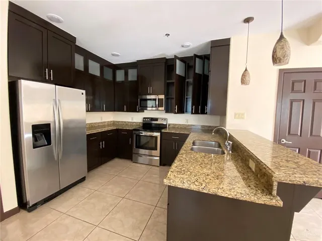 a kitchen with stainless steel appliances granite countertop a sink a stove and a refrigerator