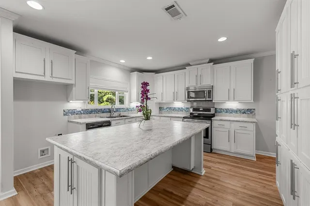 a kitchen with kitchen island granite countertop a stove sink microwave and cabinets