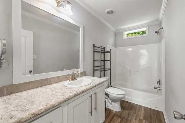 a bathroom with a granite countertop sink a toilet and shower